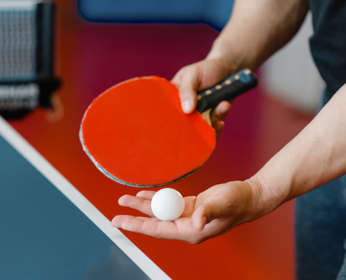 na zdjęciu zawodnik z rakietką i piłką przy stole do tenisa