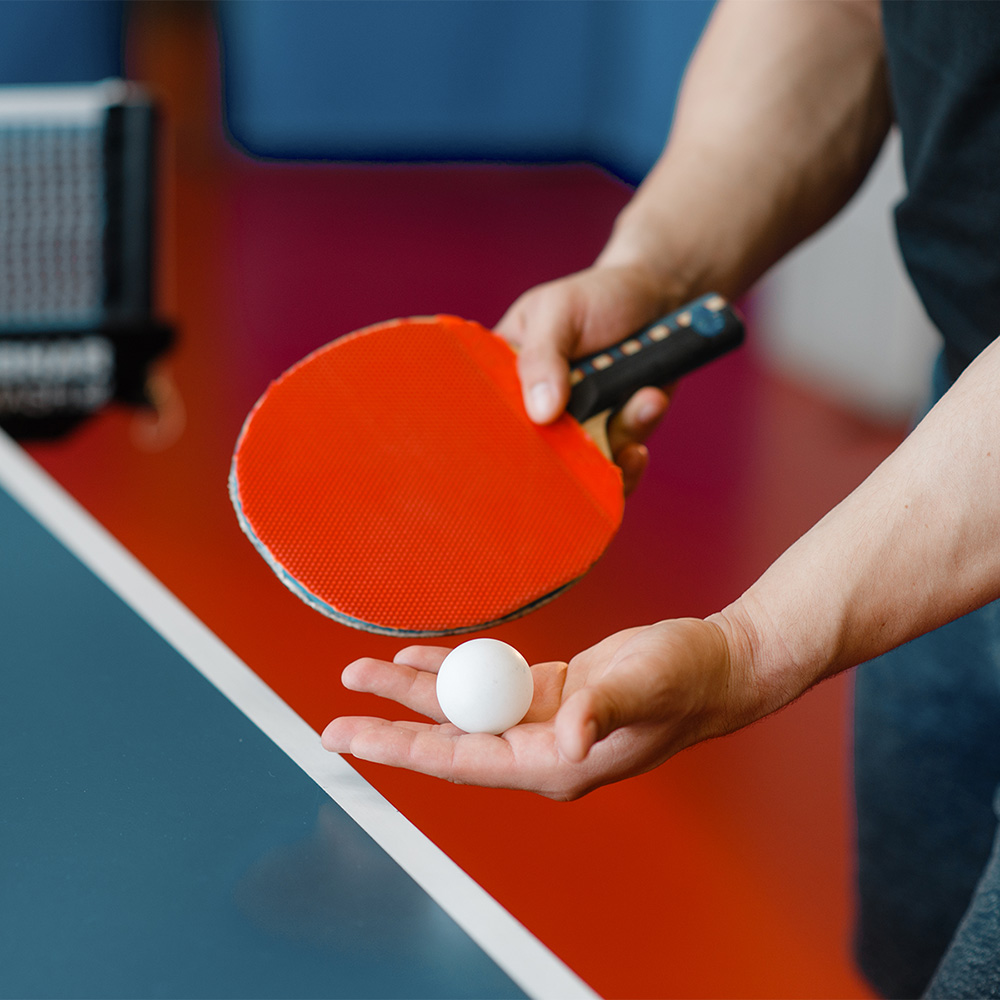 na zdjęciu zawodnik z rakietką i piłką przy stole do tenisa