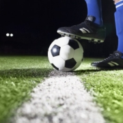 Na zdjęciu nogi piłkarza przytrzymujące piłkę nożną na murawie boiska