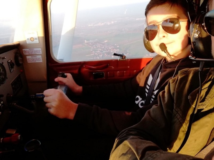 Na zdjęciu Franek Krakowczyk siedzący za sterami samolotu, w okularach przeciwsłonecznych i słuchawkach
