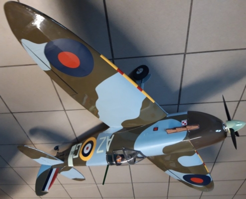 Na zdjęciu model samolotu Spitfire w kolorze moro khaki-niebieski stojący na podłodze