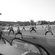 Na czarno-białym zdjęciu zajęcia fitness w parku cegielnia, w tle ćwiczący