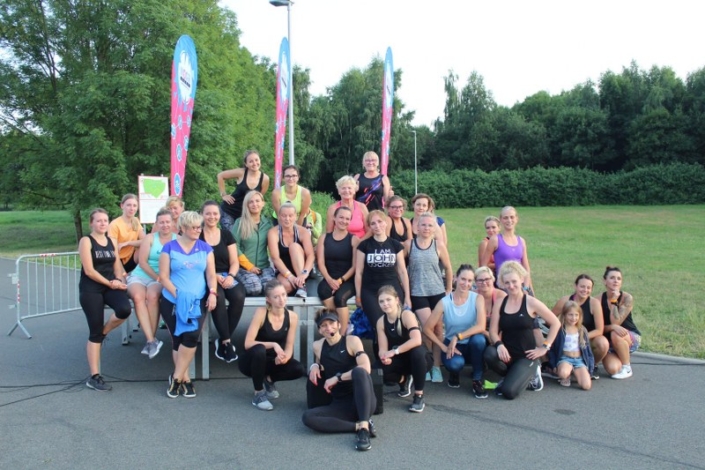 na zdjęciu grupa uczestniczek zajęć fitness z instruktorką w parku cegielnia ustawiona do zdjęcia