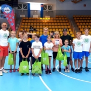na zdjęciu grupa uczestników szkółki tenisa w zdjęciu grupowym w hali sportowej