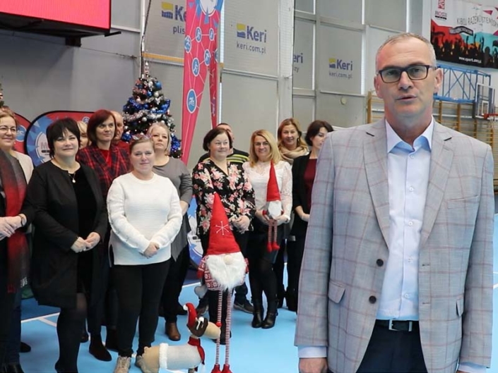 na zdjęciu dyrektor i pracownicy składający życzenia w hali sportowej