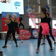 na zdjęciu grupa osób ćwiczących przed sceną w hali sportowej