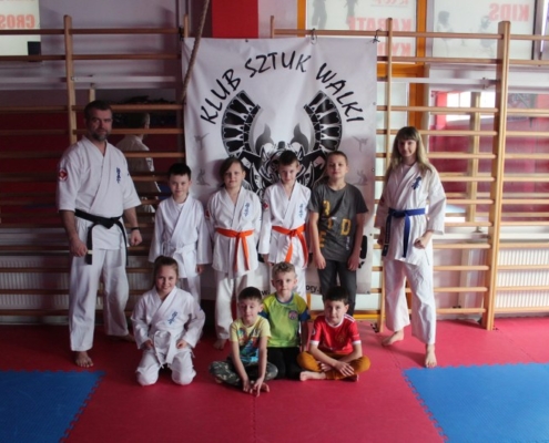 na zdjęciu uczestnicy zajęć karate w sali gimnastyczne w zdjęciu grupowym