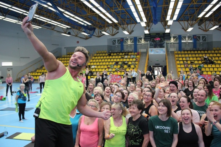 na zdjęciu w hali sportowej Daniel Qczaj robiący selfie z uczestnikami zajęć fitness