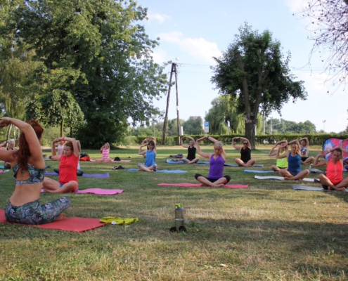 na zdjęciu zajęcia jogi na trawie obok hali sportowej