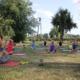na zdjęciu zajęcia jogi na trawie obok hali sportowej