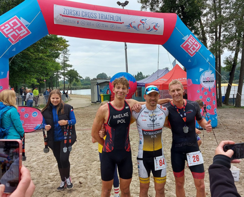 na zdjęciu zawodnicy cross triathlonu na mecie z medalami