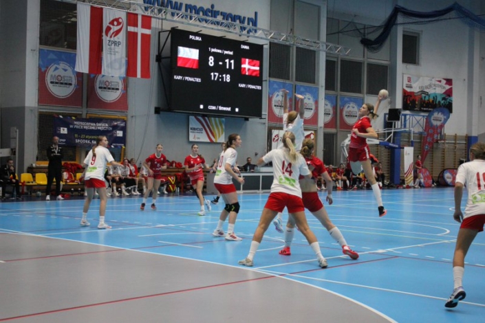 na zdjęciu mecz piłki ręcznej w hali sportowej - zawodniczka w rzucie do bramki