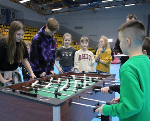 na zdjęciu grupa dzieci grająca w piłkarzyki w hali sportowej