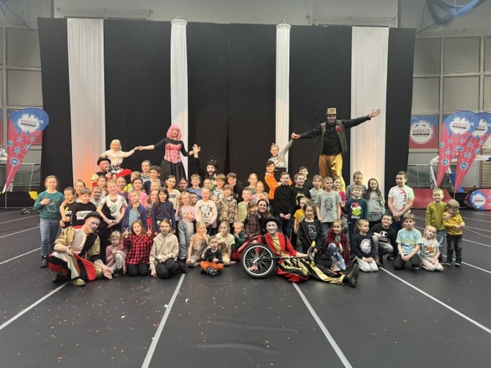 na zdjęciu grupowym w hali sportowej uczestnicy występów i grupa teatralna