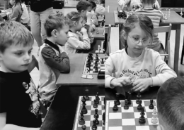 na czarno-białym zdjęciu dzieci grające w szachy w szkole