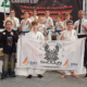 na zdjęciach zawody karate w hali sportowej i zawodnicy na podium z banerem