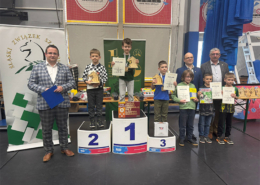 galeria zdjęć przedstawia zwycięzców zawodów szachowych na podium w żorskiej hali sportowej