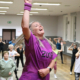 Galeria zdjęć z zajęć taneczno-fitnessowych, przedstawiająca instruktorkę prowadzącą energetyczny trening w sali oraz dzieci i dorosłych ćwiczących wspólnie choreografię.
