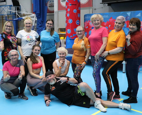 Galeria zdjęć z Aktywnego Dnia w hali sportowej – zajęcia fitness i treningi grupowe dla dorosłych, wspólna rozgrzewka i ćwiczenia na matach, animacje sceniczne oraz strefa konsultacyjno-promocyjna towarzysząca wydarzeniu.