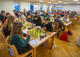 Zdjęcia przedstawiające salę wypełnioną dziećmi i młodzieżą rozgrywającymi partie szachowe przy ustawionych w rzędach stolikach podczas turnieju.