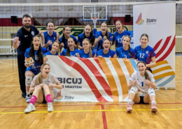 Zdjęcie drużyny siatkarek pozującej w hali sportowej po meczu – zawodniczki w niebieskich strojach wraz z trenerem trzymają baner „Kibicuj z Miastem Żory”, prezentując radość i sportowe emocje po wspólnej rywalizacji.