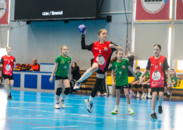 Zestaw zdjęć z dziecięcych rozgrywek sportowych w hali, przedstawiających drużynowe ujęcie uczestników oraz dynamiczną akcję meczową w trakcie gry.