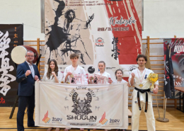 Galeria przedstawia zawody karate – ujęcia z ceremonii wręczenia nagród i zdjęć zwycięzców na podium, a także momenty prezentacji kata wykonywanych przez zawodników na macie w hali sportowej.