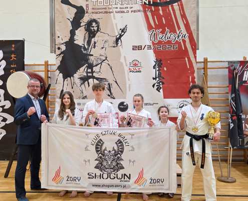 Galeria przedstawia zawody karate – ujęcia z ceremonii wręczenia nagród i zdjęć zwycięzców na podium, a także momenty prezentacji kata wykonywanych przez zawodników na macie w hali sportowej.