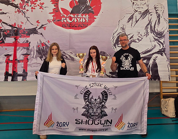 Galeria przedstawia zawodników klubu Shogun podczas turnieju karate kyokushin. Na zdjęciach widoczne są walki na macie, prezentacje kata, dekoracje medalowe oraz wspólne fotografie uczestników i trenerów.