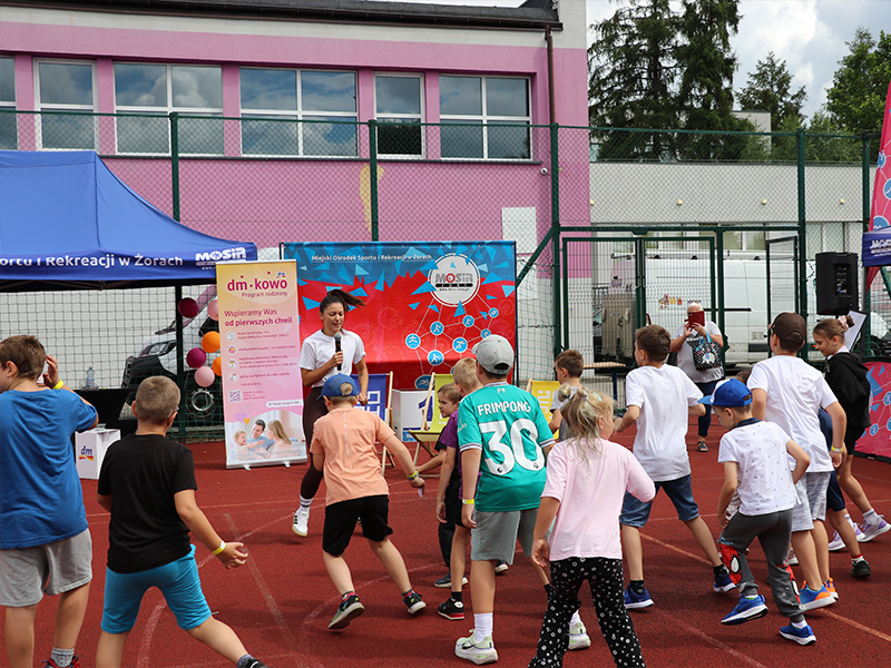 Galeria zdjęć z rodzinnego festynu sportowo-rekreacyjnego, przedstawiająca dzieci uczestniczące w konkurencjach, animacjach, grach, warsztatach i zabawach na świeżym powietrzu.