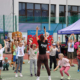 Galeria zdjęć z rodzinnego pikniku sportowego, przedstawiająca dzieci i rodziny korzystające z atrakcji, konkursów, dmuchańców, animacji oraz stref aktywności na świeżym powietrzu.